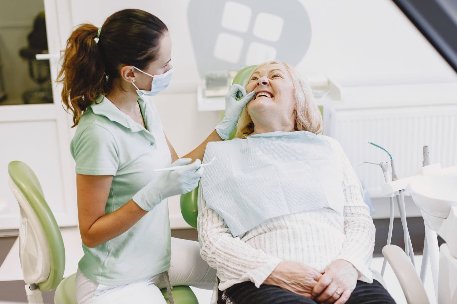 Patiente assise dans un fauteuil dentaire, dentiste en tenue de bloc à ses côtés